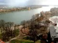 Widok na jezioro nadrowskie z wyspą i zabudowaniami. Drzewa bez liści, jesienny krajobraz.