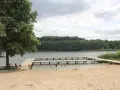 Plaża nad jeziorem Zaleskim z drewnianymi pomostami, na których bawią się ludzie.