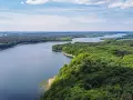 Malownicze jezioro otoczone lasem, idealne miejsce na nietypowe atrakcje Mazury. Widok z lotu ptaka na spokojną taflę wody i bujną zieleń.