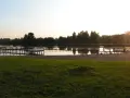 Drewniane pomosty na spokojnym jeziorze starogrodzkim, z piaszczystą plażą i zieloną trawą w tle.