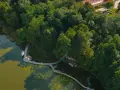 Żaglówka i deska SUP na spokojnym jeziorze ostrowskim, otoczonym bujną zielenią i drewnianą kładką.