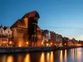 Wieczorny widok na Żuraw i zabytkowe kamienice w Gdańsku. Idealne miejsce, gdzie pociągiem z Krakowa można poczuć ducha historii.