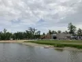 Spokojne jezioro małe żnińskie z piaszczystą plażą, budynkiem CSW i zielenią w tle.