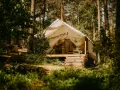 Namiot na Mazurach, otoczony lasem. Drewniana ławka i taras zapraszają do odpoczynku. Idealne miejsce na mazury pod namiot.