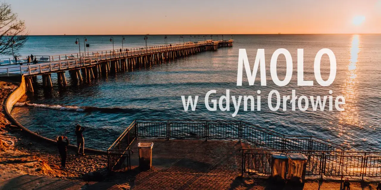Zachód słońca nad morzem, długie molo w Orłowie, ludzie spacerują po plaży.