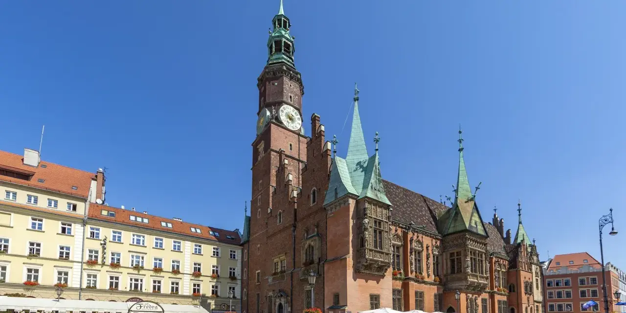 Rynek we Wrocławiu z Ratuszem, gdzie mieści się muzeum sztuki mieszczańskiej. Wokół kawiarnie i ludzie spacerujący.