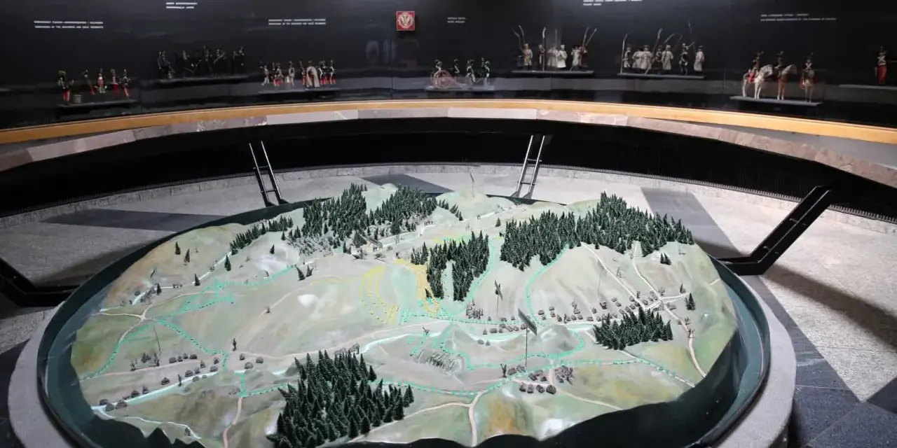 Model terenu przedstawiający bitwę pod Racławicami. Na tle miniatury żołnierzyków w historycznych strojach.