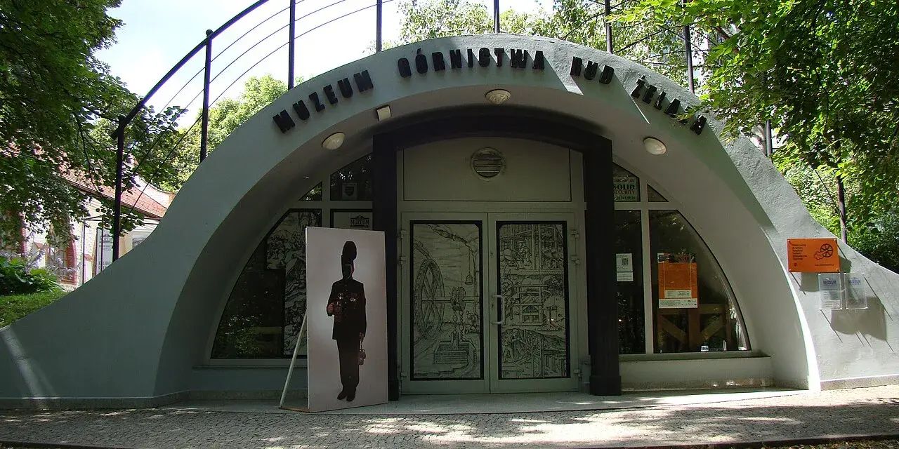 Wejście do Muzeum Górnictwa Rud Żelaza. Przed budynkiem stoi wielkoformatowy portret górnika.