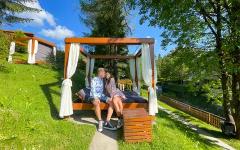 Para zakochanych na łóżku pod baldachimem, idealny pomysł na weekend w otoczeniu zieleni i strumyka.