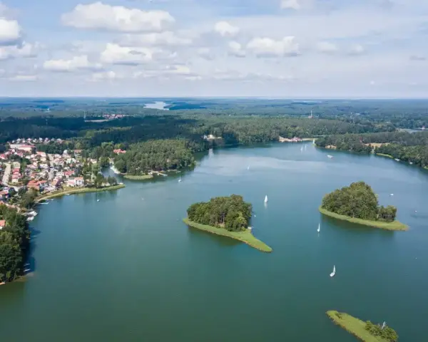 Malownicze jezioro z wyspami i żaglówkami, otoczone lasem i zabudowaniami. To widok, który potwierdza, że to jedne z najpiękniejszych jezior w Polsce.