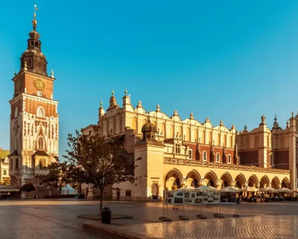 Rynek Główny w Krakowie, idealne miejsce na city break. Sukiennice i wieża Ratuszowa w słońcu.