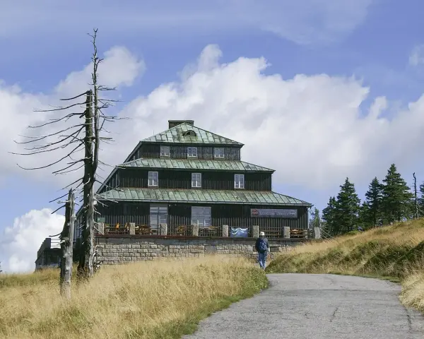 Schronisko Odrodzenie w Karkonoszach, z charakterystyczną architekturą i otoczone suchymi drzewami.