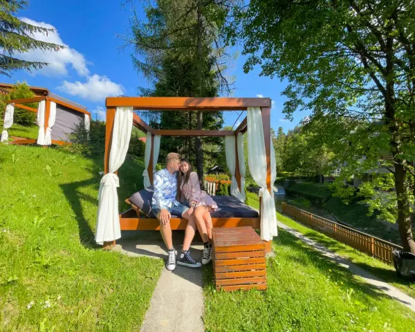 Para zakochanych na łóżku pod baldachimem, idealny pomysł na weekend w otoczeniu zieleni i strumyka.