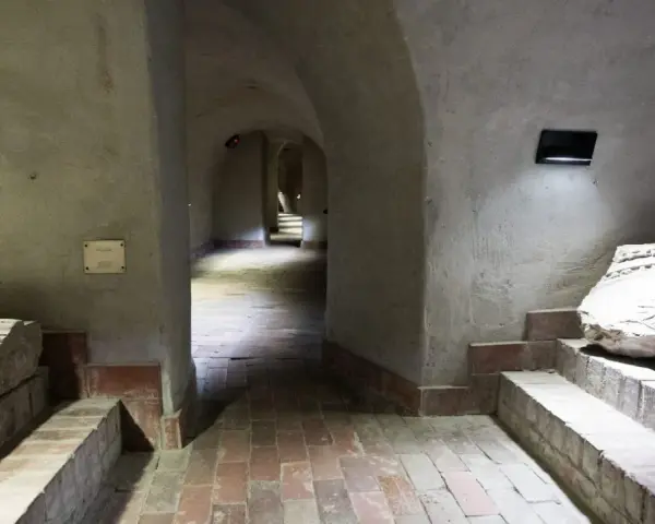 Kamienne korytarze i łuki tworzą tajemniczą trasę podziemną w Lublinie. Widać fragmenty dawnych budowli i artefakty.