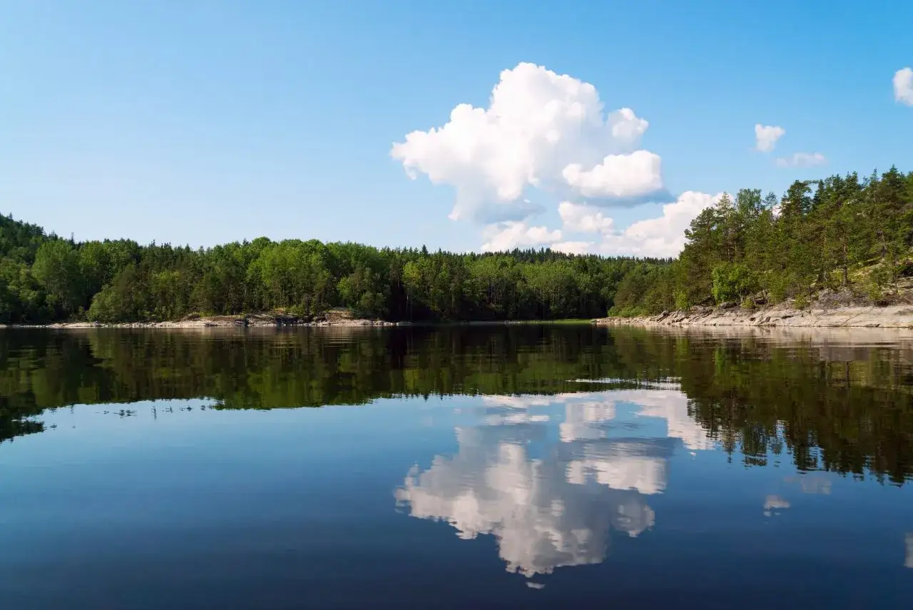 Spokojne jezioro z odbijającymi się chmurami i lasem. Idealne miejsce na weekendowy wypad na Mazury blisko Warszawy.