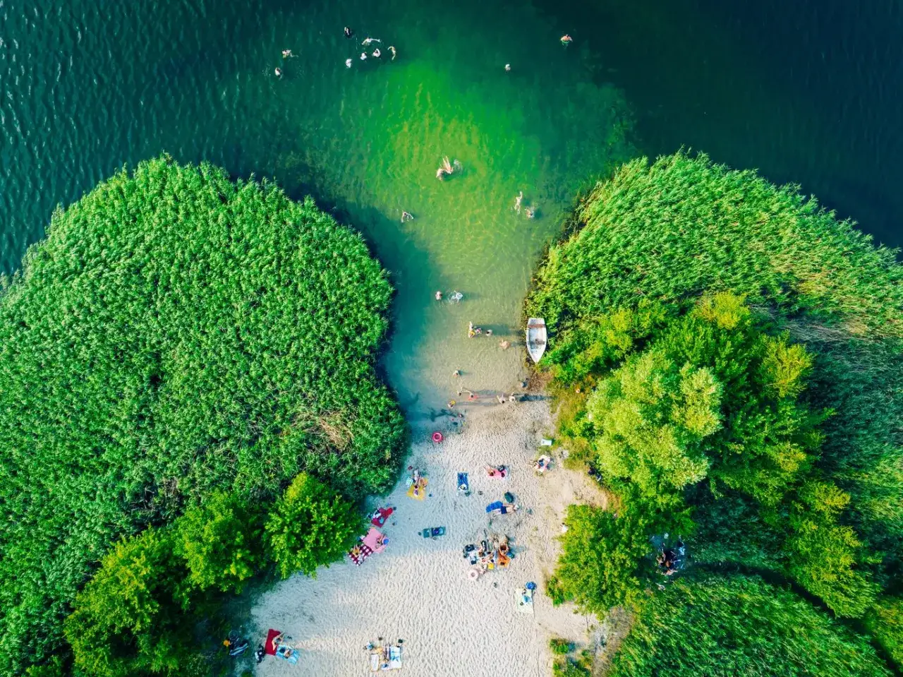 Letnia kąpiel w jednym z najpiękniejszych jezior w Polsce. Ludzie relaksują się na piaszczystej plaży i pływają w krystalicznie czystej wodzie.