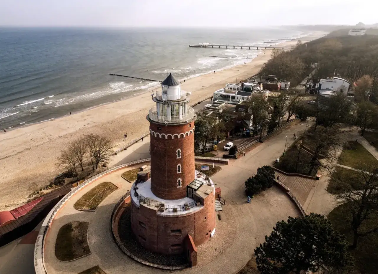 Ceglana latarnia morska góruje nad plażą i Bałtykiem. To jedna z atrakcji nad morzem bałtyckim, idealne miejsce na spacer.