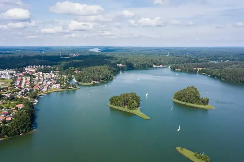 Malownicze jezioro z wyspami i żaglówkami, otoczone lasem i zabudowaniami. To widok, który potwierdza, że to jedne z najpiękniejszych jezior w Polsce.
